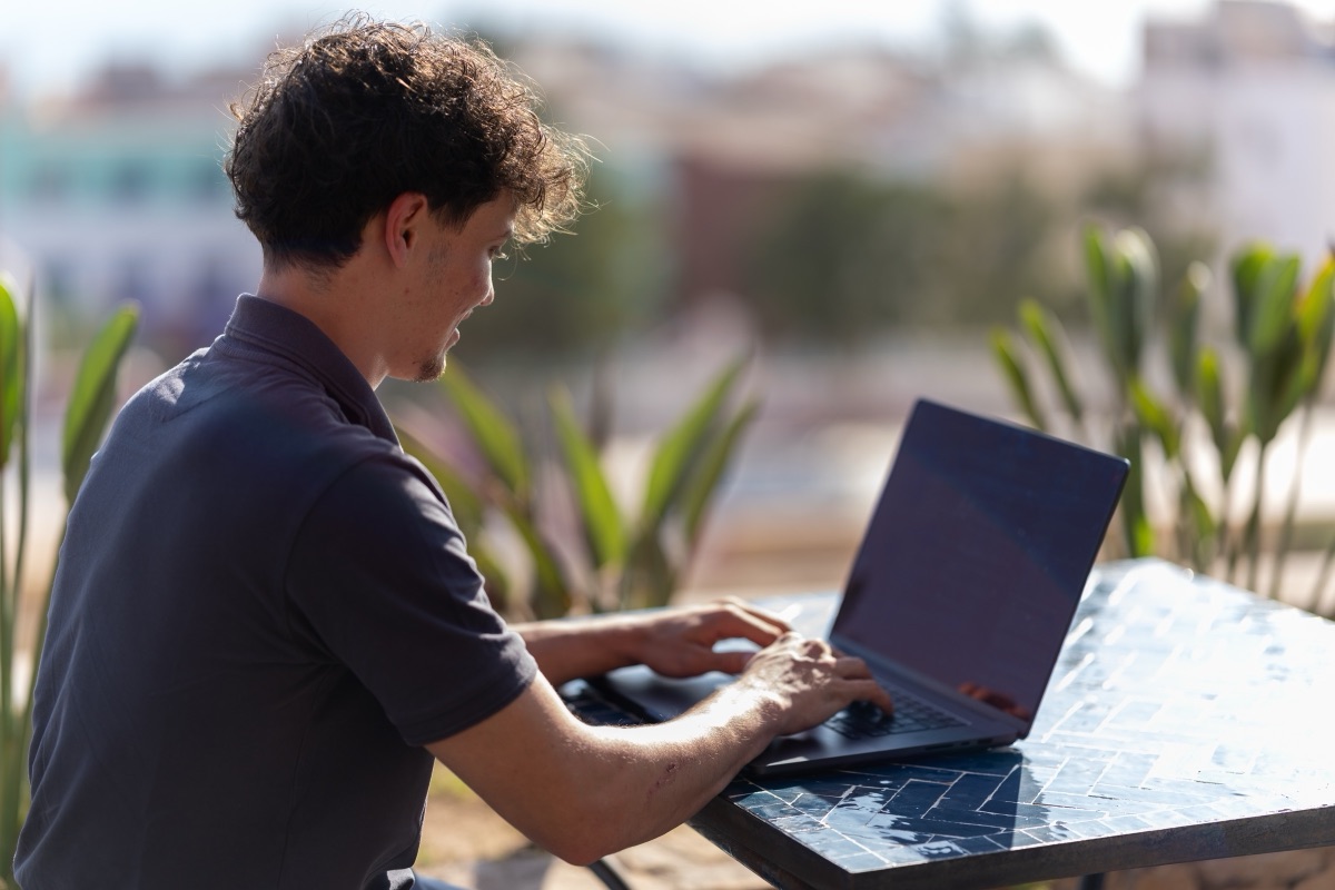 Alec Baab sitzt draußen am Laptop und arbeitet